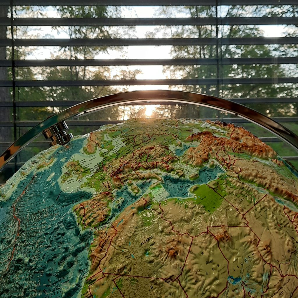 Das Bild zeigt einen Ausschnitt des Reliefglobus im Geographieraum des Otto-Hahn-Gymnasiums. Im Hintergrund sieht man das Fenster und die aufgehende Sonne.
