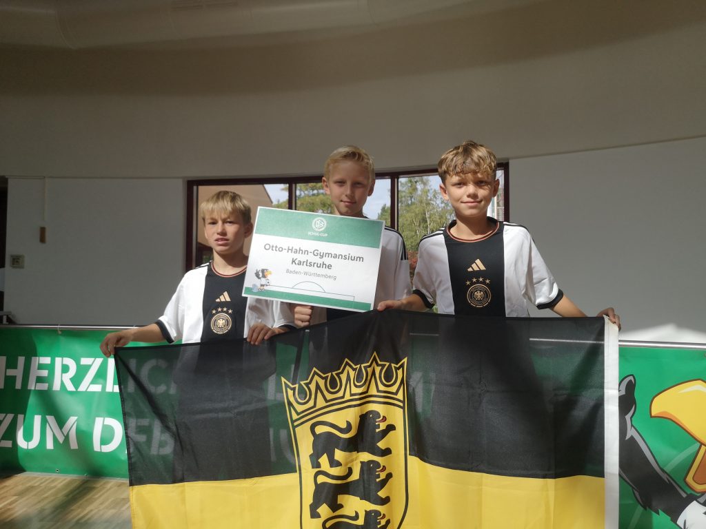 Drei Schüler vor dem BW - Wappen mit Siegerurkunde.