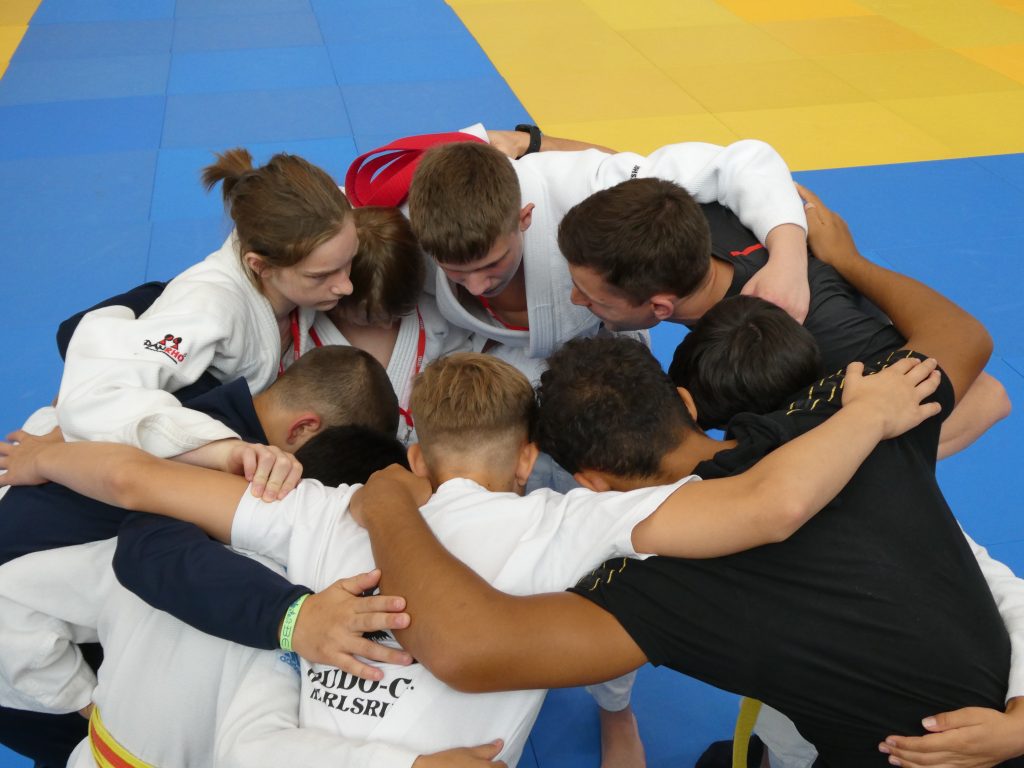 Team-Geist - alle bilden einen Kreis - die Hände auf den Schultern - Trainer A. Braun motiviert.