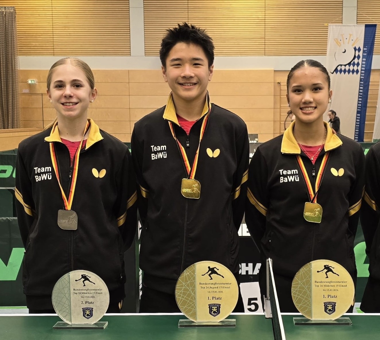 Drei stolze GewinnerInnen in schwarzen Trikots - die Medaillen um den Hals