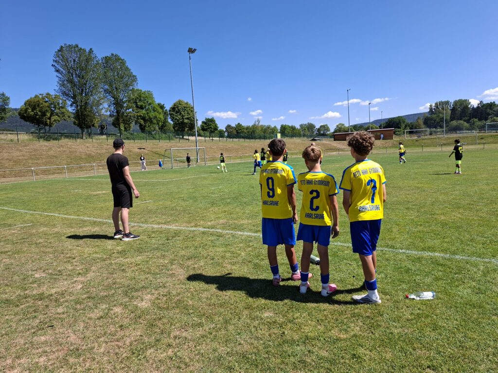 Fußballfeld - 3 Spieler im gelben Trikot und Herr Bichelhuber